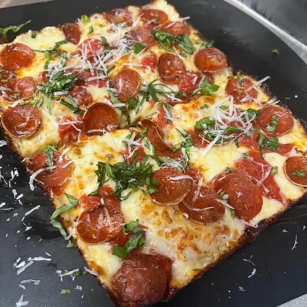 A square pepperoni pizza from Sodough Square, topped with melted cheese, fresh basil, and grated parmesan.