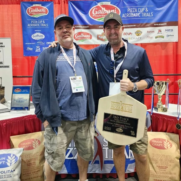 Two men from Sodough Square proudly display their 3rd place pizza competition award.