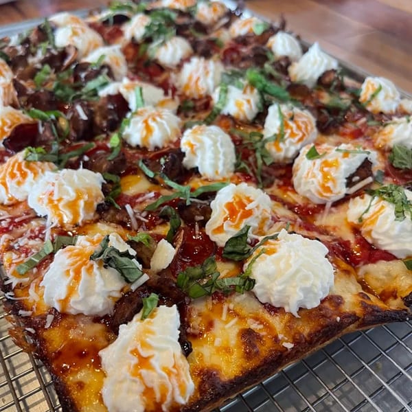 Sodough Square pizza with dollops of ricotta, basil, and a drizzle of orange sauce.